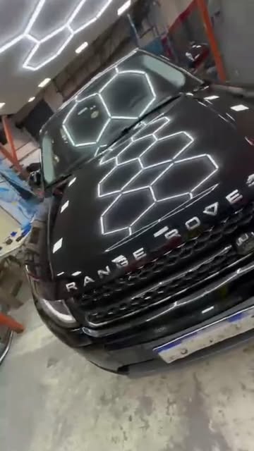 Auto negro dentro del taller con iluminación de detailing